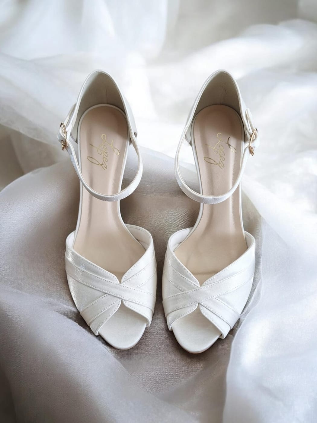 Sandália branca peep toe de tiras cruzadas com a marca Lopez dourada na palmilha, sobre tecido